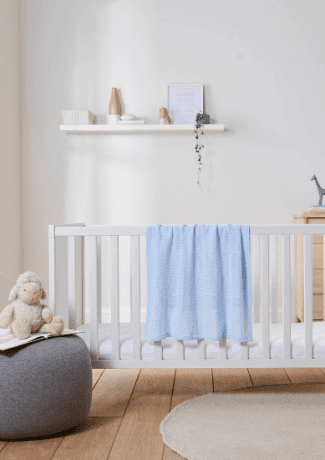 Blue blanket hanging over cot in nursery