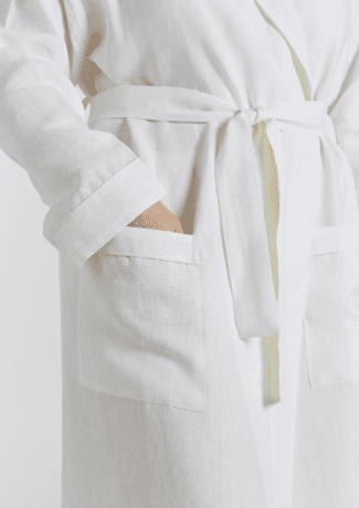 Close up of a white bathrobe worn by woman with her hand in pocket